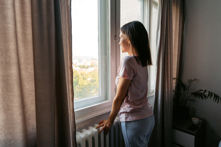 Young Woman Looking Out The Window After Waking Up In The Morning